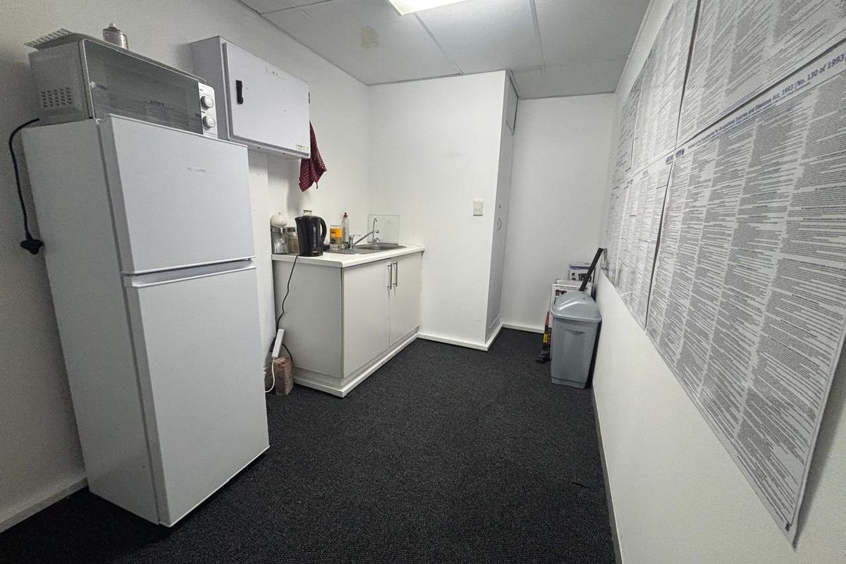 A functional office kitchenette featuring a small sink, base cabinetry, and a drop ceiling with integrated lighting.