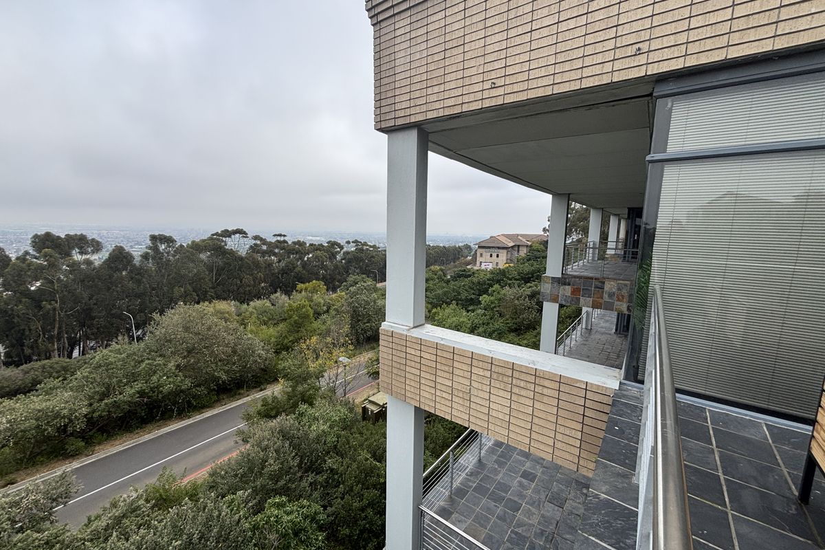 Exterior view of the office building facade featuring multi-level balconies with slate tiling and metal railings overlooking the surrounding landscape.