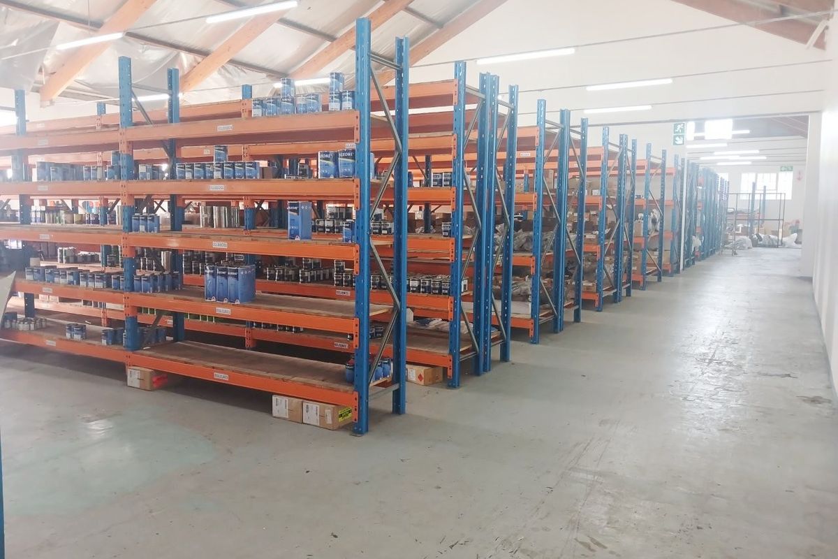 Industrial warehouse space featuring high-clearance ceilings, exposed timber trusses, and extensive rows of heavy-duty steel pallet racking for efficient storage.