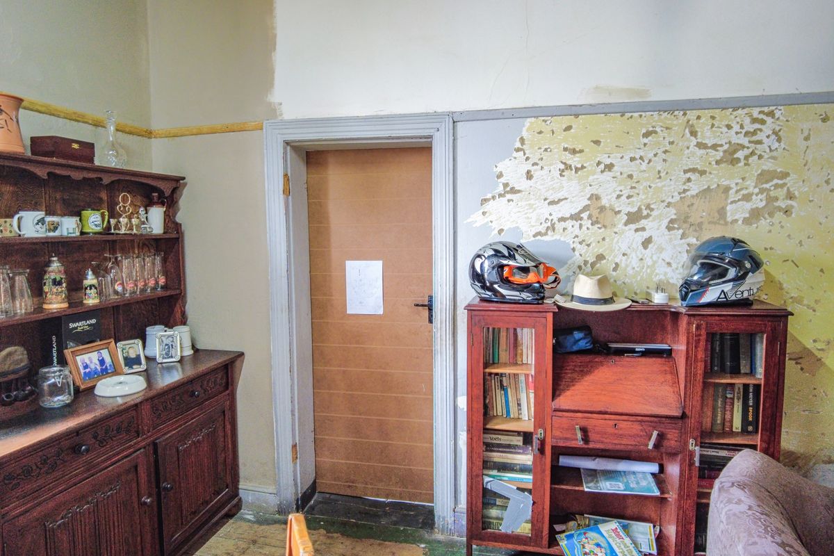 Interior living space featuring a timber door and significant wall finish deterioration requiring repair and redecoration.