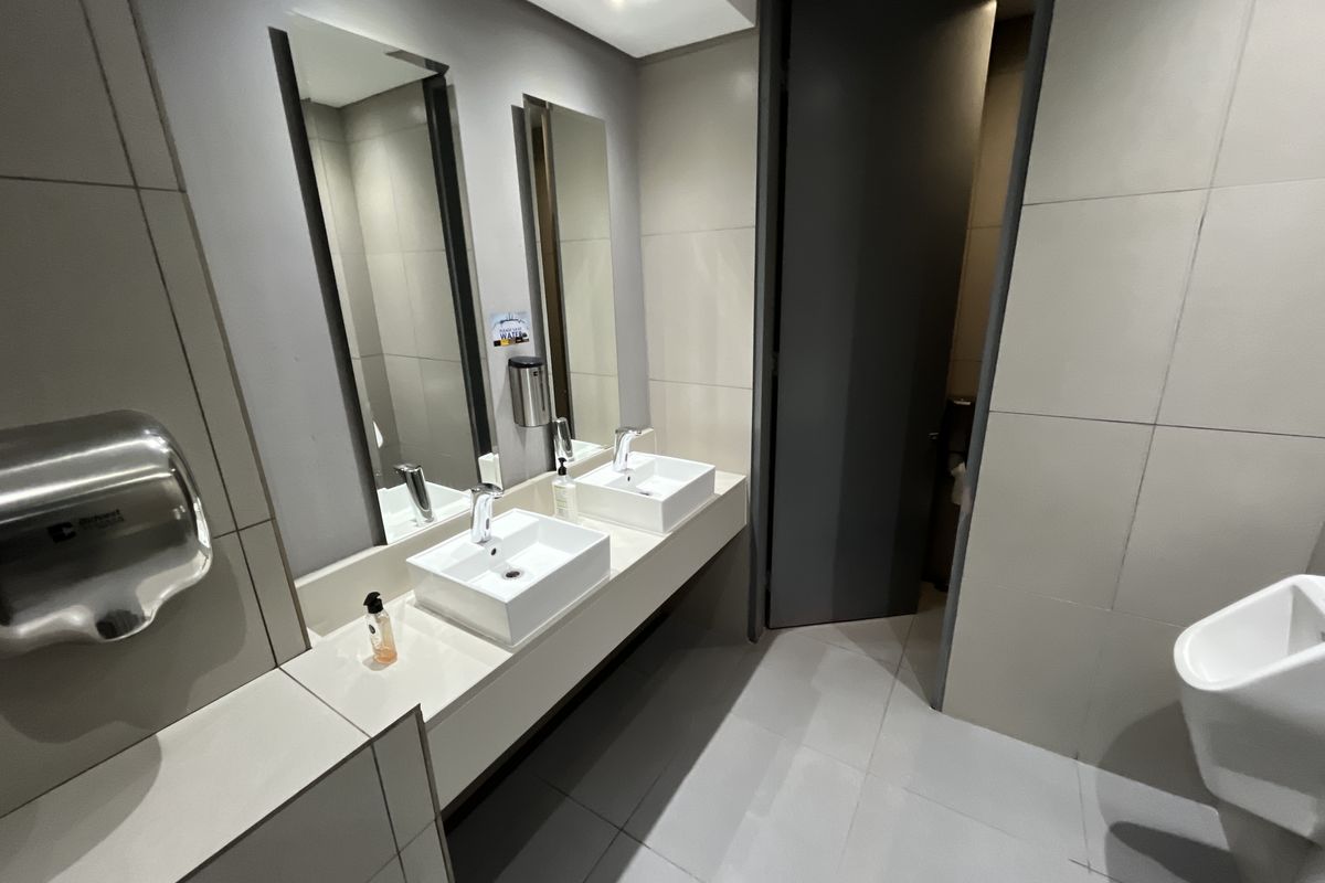 Modern office restroom featuring dual vessel sinks, wall-mounted mirrors, and a clean tiled finish.