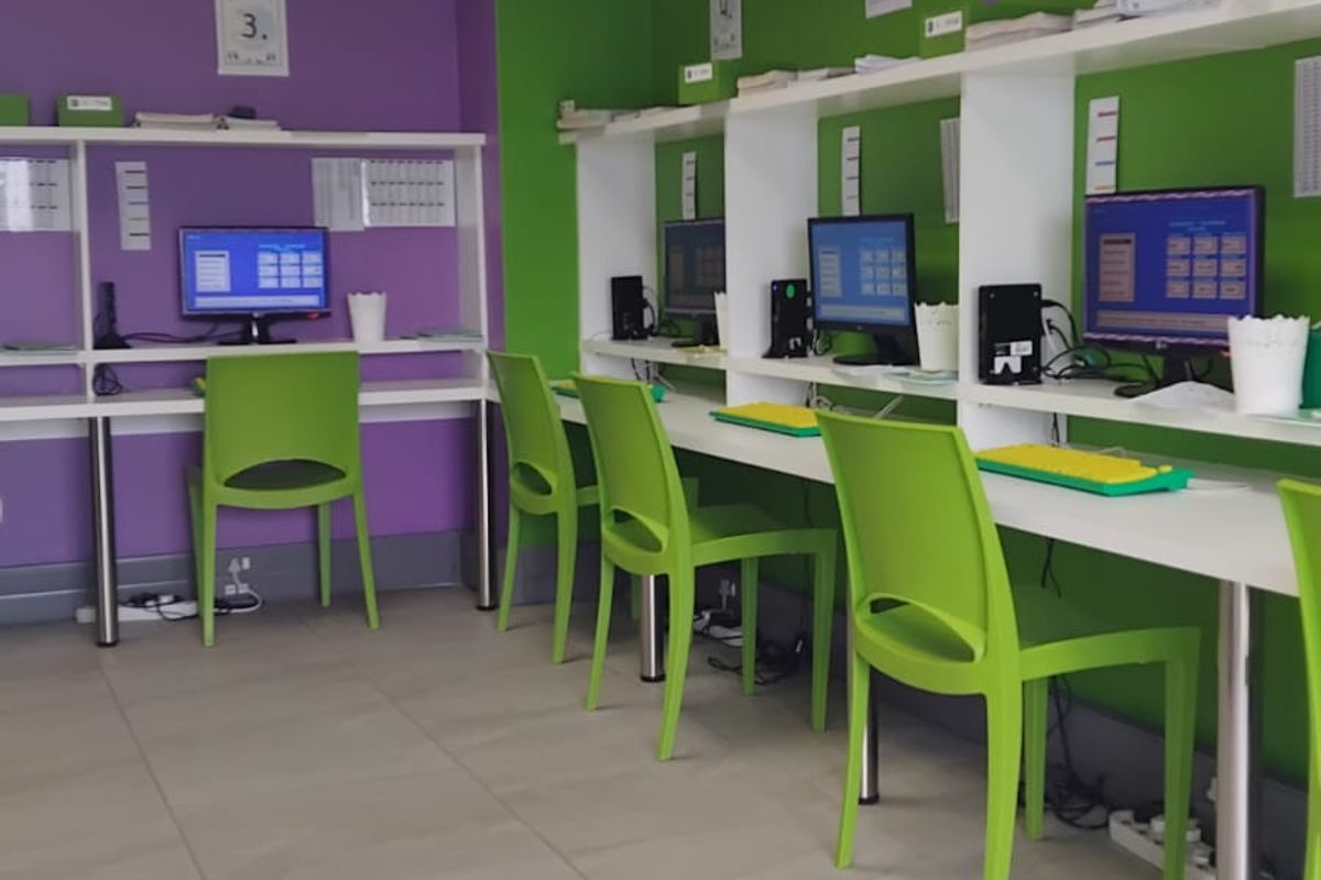 A functional office space featuring multiple built-in desk workstations, tiled flooring, and recessed ceiling lighting, suitable for a collaborative work environment.