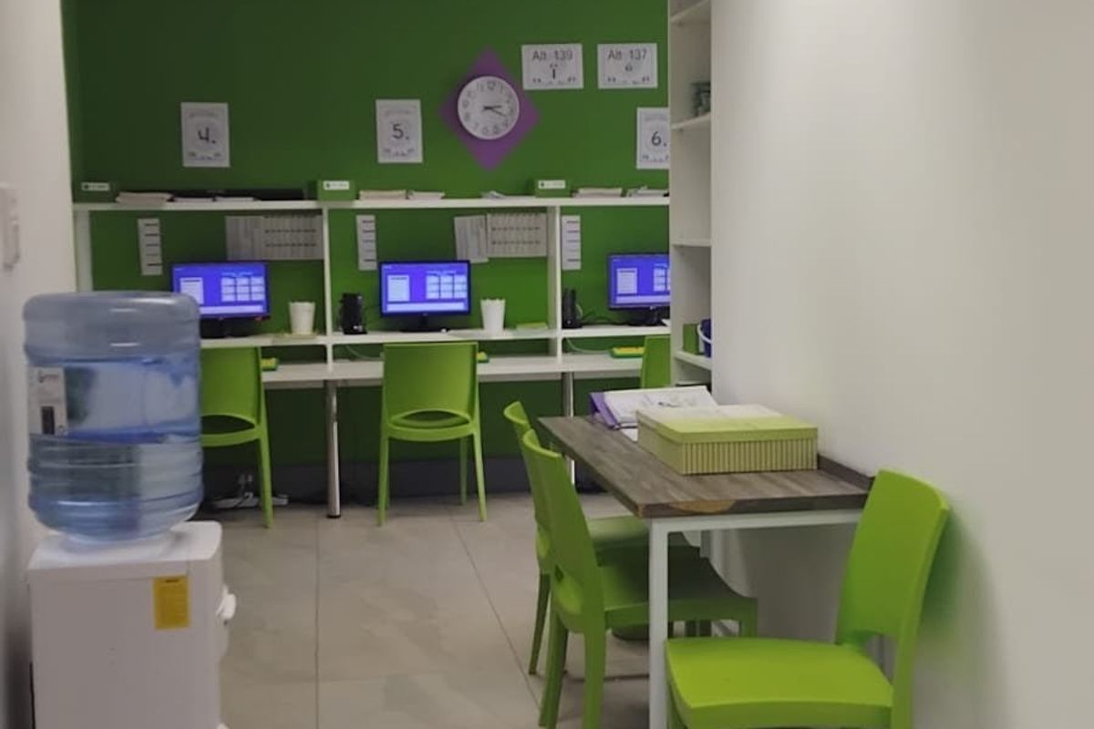 A functional office space featuring a built-in desk workstation, tiled flooring, and recessed ceiling lighting, providing a practical environment for professional tasks.