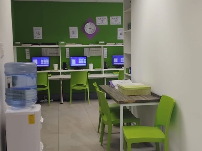 A functional office space featuring a built-in desk workstation, tiled flooring, and recessed ceiling lighting, providing a practical environment for professional tasks.