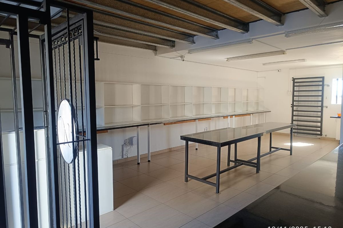 Commercial utility space featuring tiled flooring, built-in wall shelving, and exposed ceiling structure, suitable for storage or workshop use.