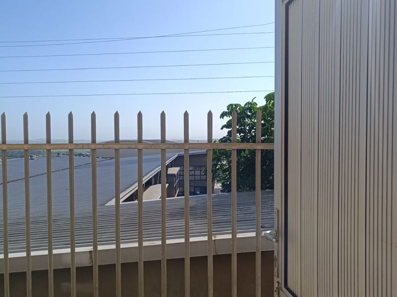 View from an elevated position overlooking a commercial building roof with metal security fencing in the foreground.