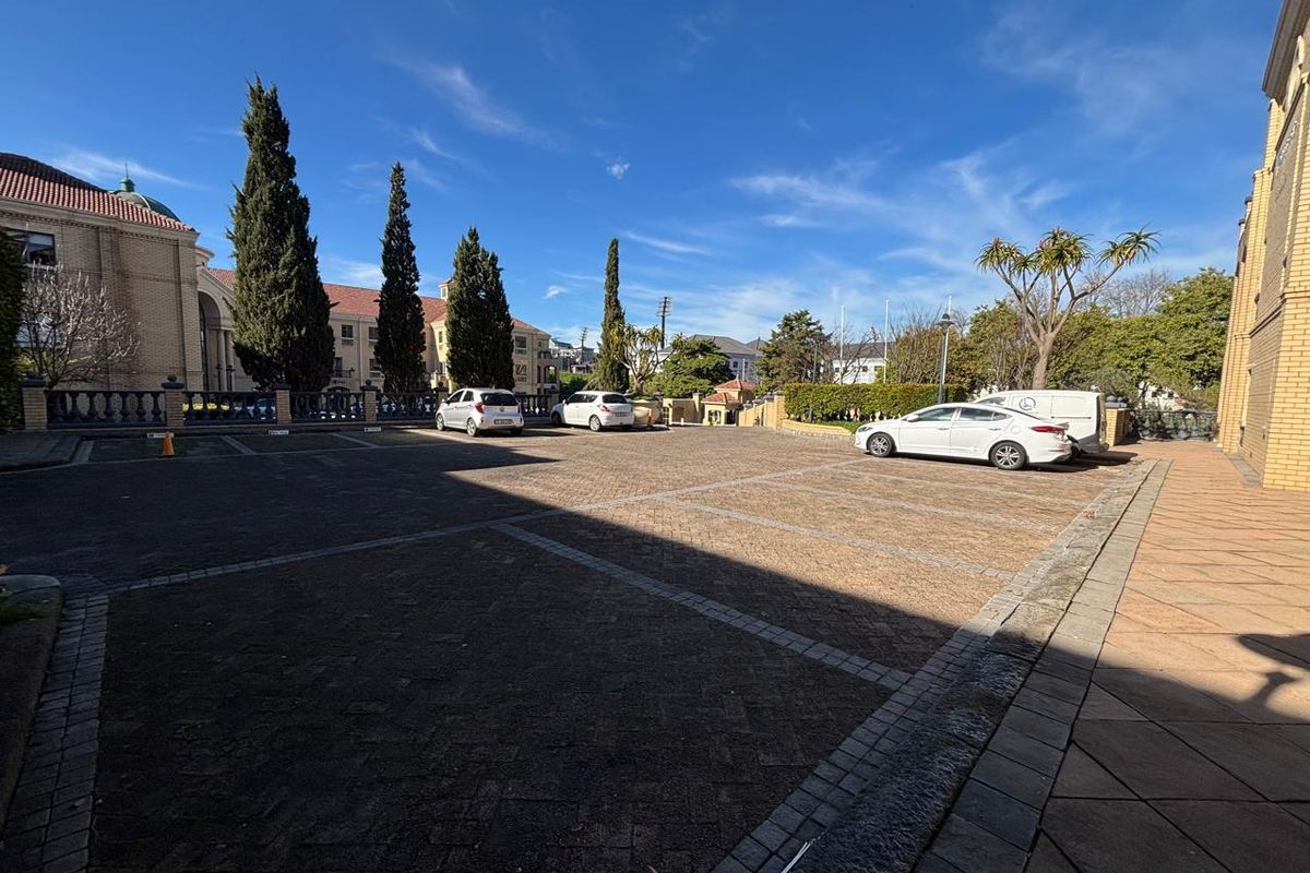 A paved outdoor parking area situated between office buildings, featuring marked parking bays and landscaped surroundings.