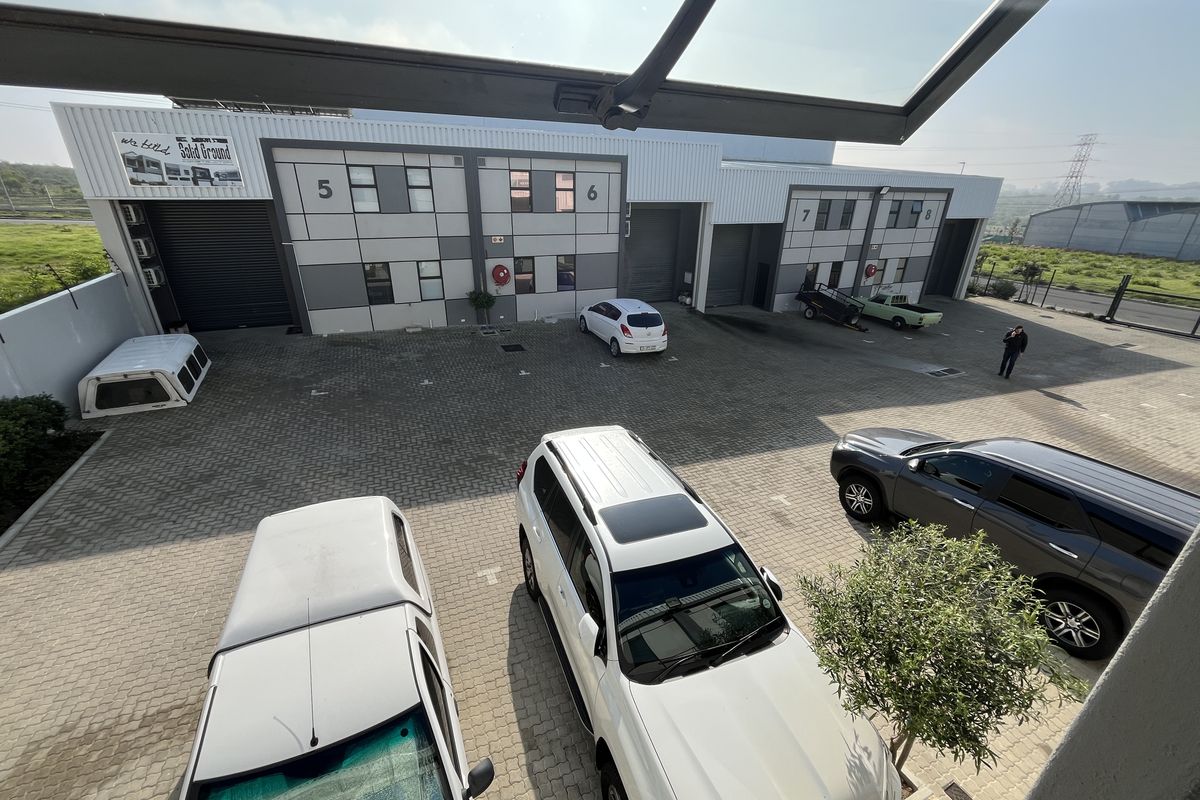 Elevated view of an industrial complex courtyard featuring paved parking areas and multiple roller shutter door access points for units five through eight.