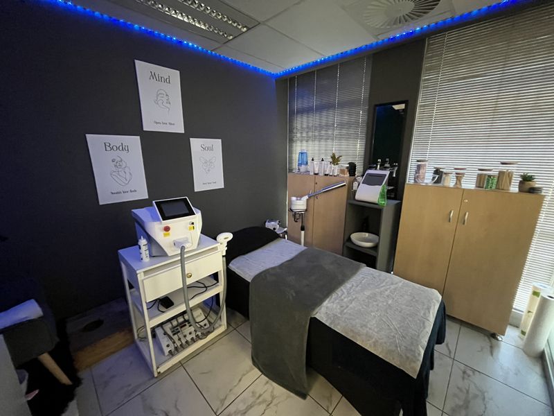 A functional office or treatment room featuring tiled flooring, built-in cabinetry, and recessed ceiling lighting with ambient blue accent lighting.