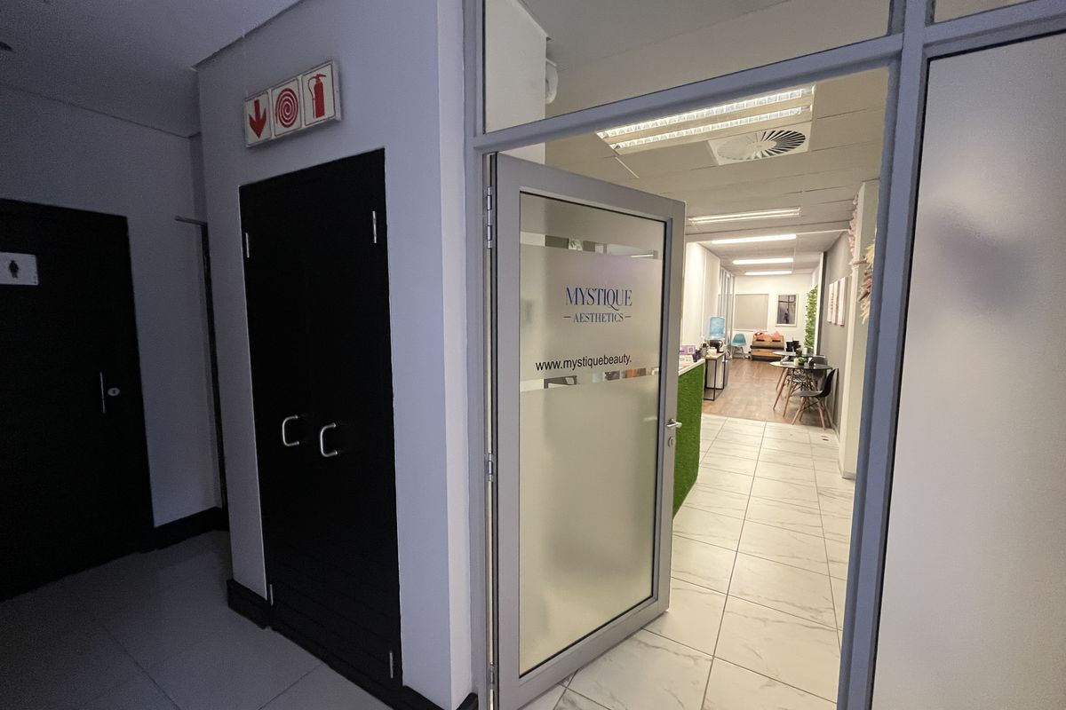 Entrance area to a professional office suite featuring a glass-panelled door, tiled flooring, and integrated fire safety infrastructure.