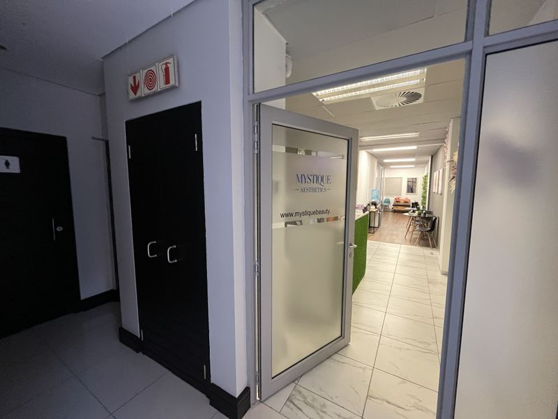 Entrance area to a professional office suite featuring a glass-panelled door, tiled flooring, and integrated fire safety infrastructure.