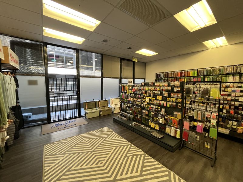 A well-lit commercial office or retail space featuring large windows, recessed ceiling lights, and durable laminate flooring, currently utilized for product display.