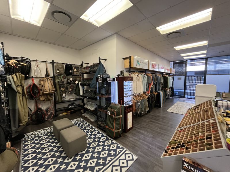 A well-lit retail office space featuring laminate flooring, suspended ceilings with recessed lighting, and extensive built-in wall shelving for product display.