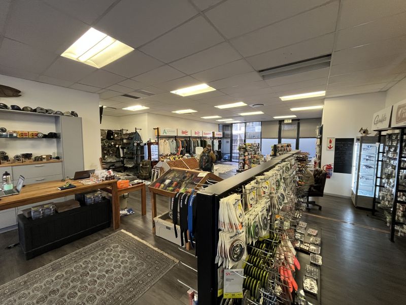 A well-lit commercial office space currently utilized as a retail showroom, featuring suspended ceilings, recessed lighting, and durable laminate flooring.