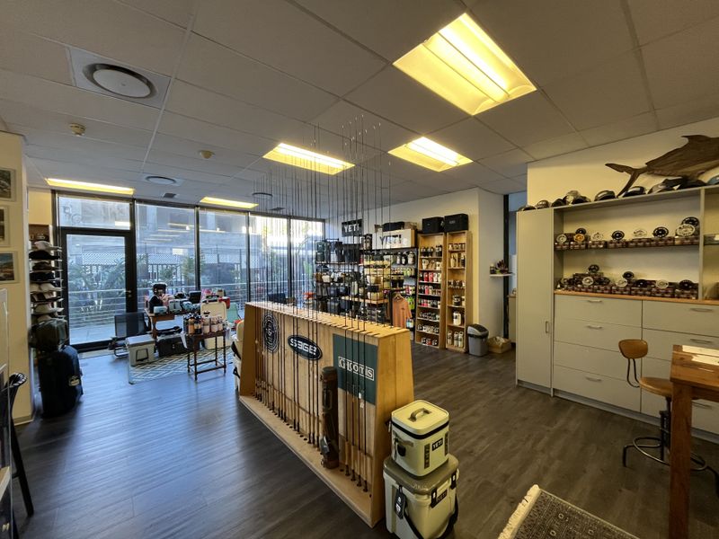 A well-lit office or retail space featuring a suspended ceiling, large glass windows, and built-in storage cabinetry with modern laminate flooring.