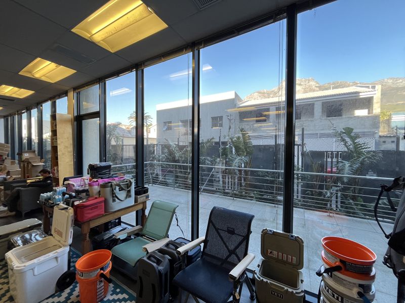 Bright office space featuring expansive floor-to-ceiling windows with views of the exterior balcony and surrounding neighborhood.