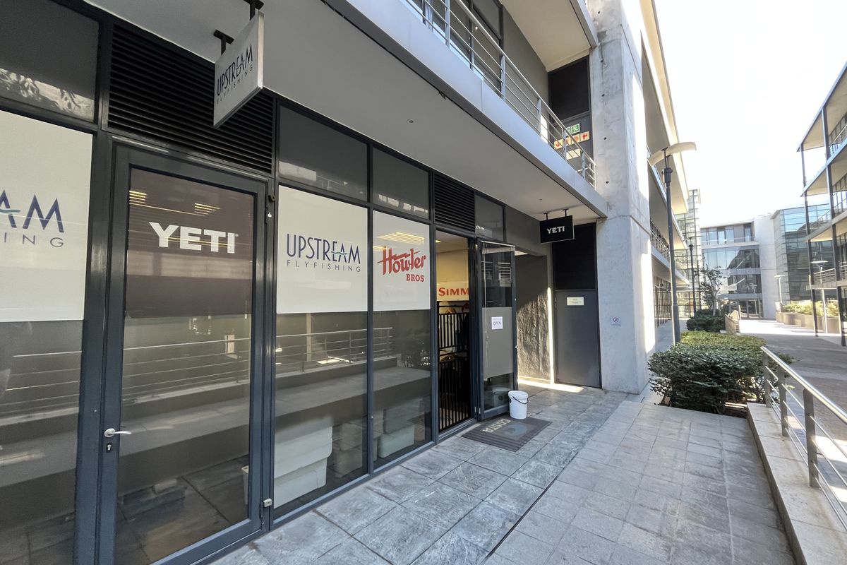 Modern commercial office storefront with large glass windows, aluminum framing, and a paved pedestrian walkway in a contemporary office park setting.
