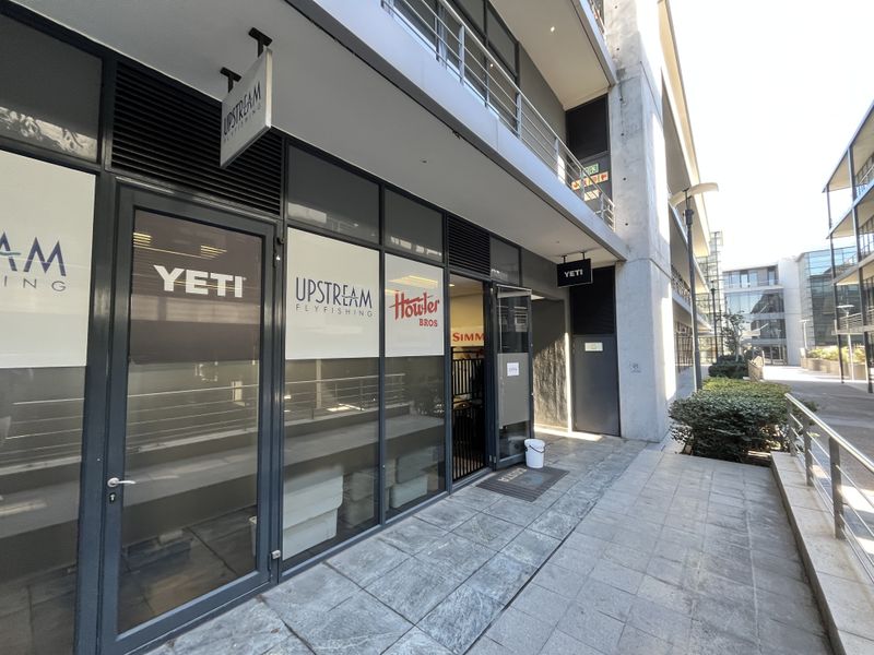Modern commercial office storefront with large glass windows, aluminum framing, and a paved pedestrian walkway in a contemporary office park setting.