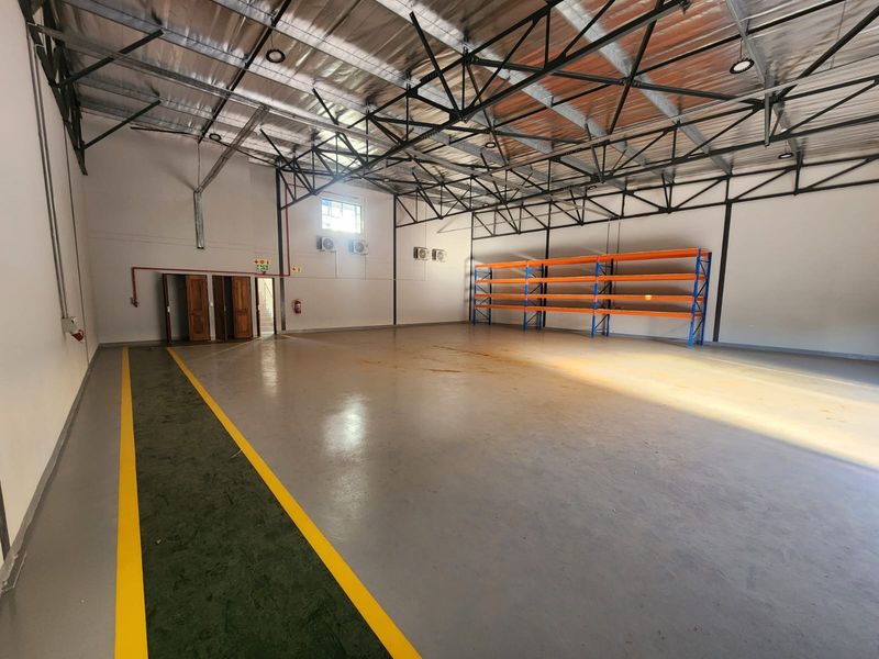 Spacious industrial warehouse unit featuring high ceilings with exposed steel trusses, durable epoxy flooring, and integrated heavy-duty storage racking.