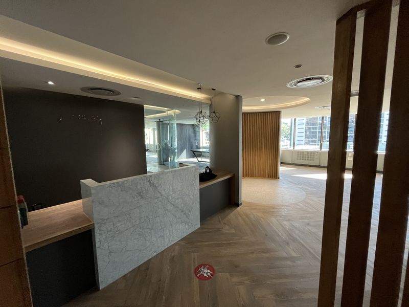 Modern office reception area featuring a marble desk, herringbone timber flooring, and elegant timber slat accents with recessed ceiling lighting.