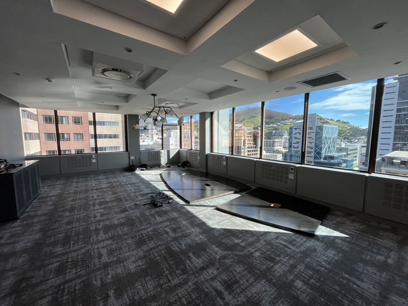 Spacious, modern office suite featuring floor-to-ceiling windows with panoramic city and mountain views, recessed lighting, and integrated climate control systems.