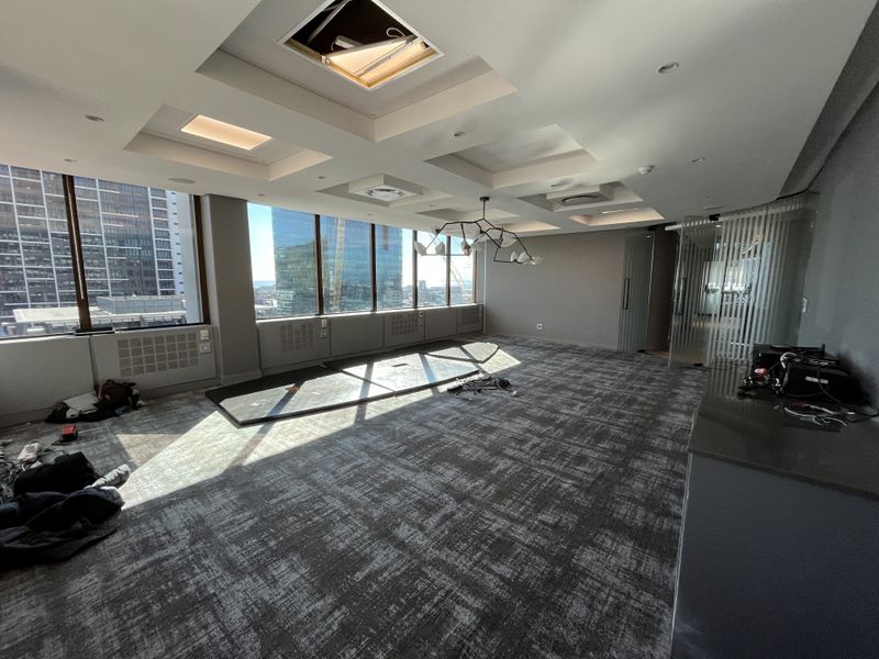 Spacious modern office suite featuring floor-to-ceiling windows with city views, recessed ceiling lighting, and a glass partition wall.
