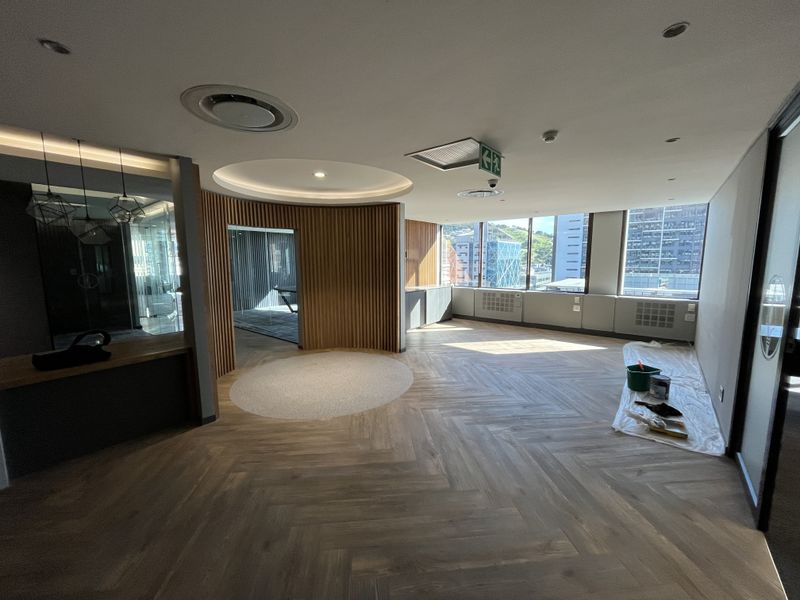 Modern open-plan office space featuring high-end herringbone timber flooring, elegant timber slat wall detailing, and expansive windows offering natural light and city views.