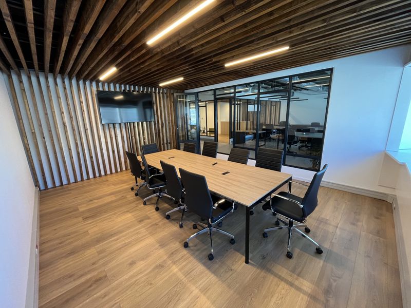 Modern professional boardroom featuring a slatted timber ceiling and wall feature, glass partition wall, and high-quality laminate flooring.