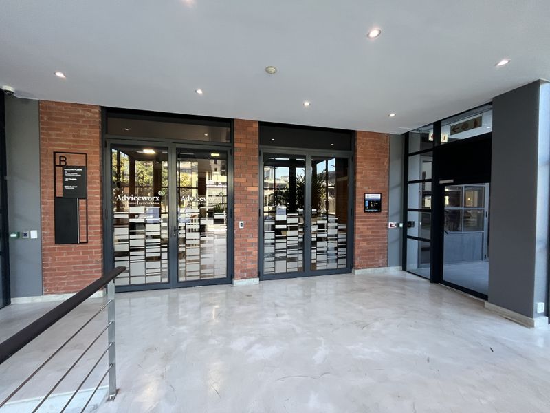 Modern office building entrance featuring polished concrete floors, exposed brick accents, and glass-paneled double doors with professional signage.