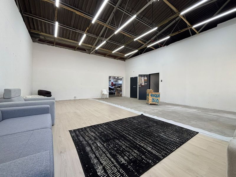 Spacious industrial utility area featuring exposed roof trusses, linear LED lighting, and a combination of laminate and concrete flooring.