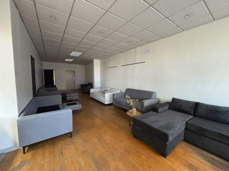 Spacious living area featuring a suspended ceiling with recessed lighting and timber flooring, offering a versatile layout for various industrial or commercial uses.