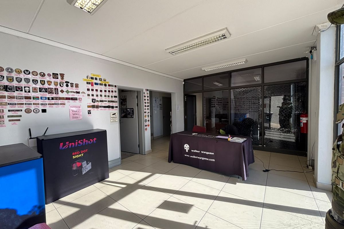 A functional office or commercial reception area featuring tiled flooring, fluorescent lighting, and a glass partition wall.