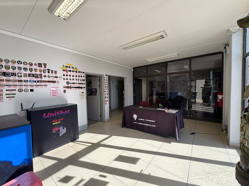 A functional office or commercial reception area featuring tiled flooring, fluorescent lighting, and a glass partition wall.