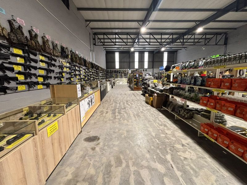 Spacious industrial retail unit featuring exposed steel roof trusses, high-bay lighting, and durable concrete flooring, currently configured for specialized equipment display.