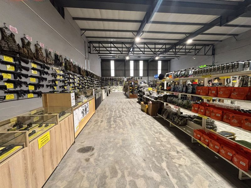 Industrial warehouse space featuring exposed steel roof trusses, high bay lighting, and concrete flooring, currently utilized as a retail display area.