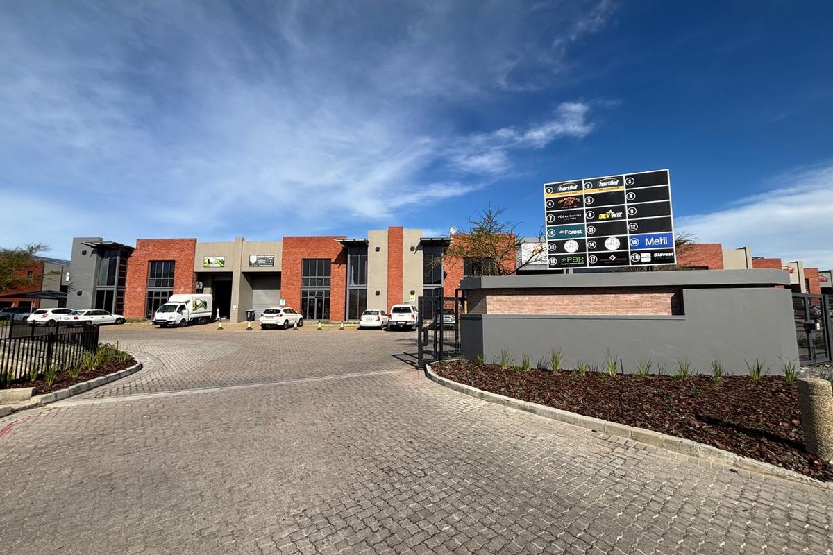Front view of a modern industrial business park featuring brick facade units, paved driveway, and a prominent commercial directory signage board.