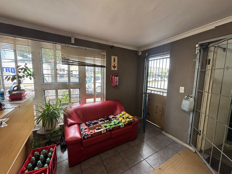 An industrial entry area featuring tiled flooring, security gates, and a fire extinguisher, providing a functional access point for the property.