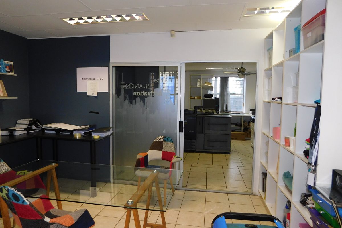 A functional office space featuring tiled flooring, built-in shelving, and a sliding glass door leading to an adjacent workspace.