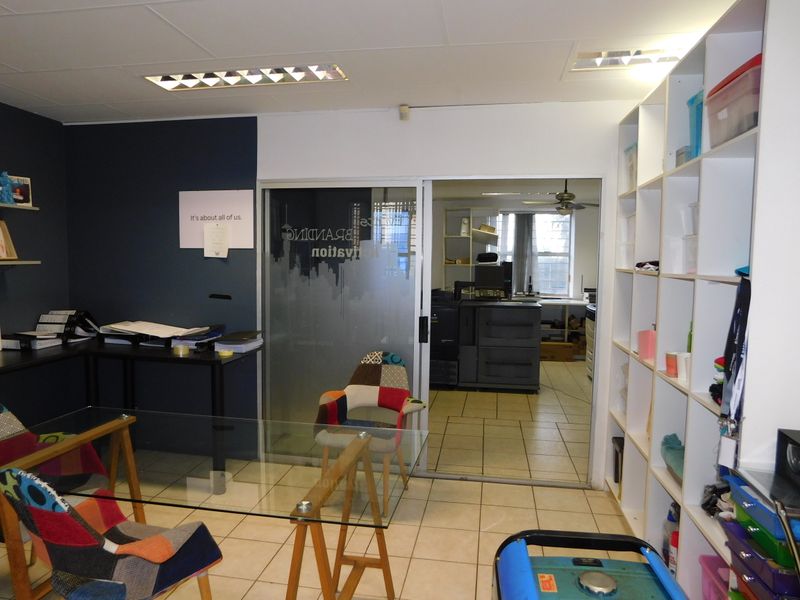 A functional office space featuring tiled flooring, built-in shelving, and a sliding glass door leading to an adjacent workspace.