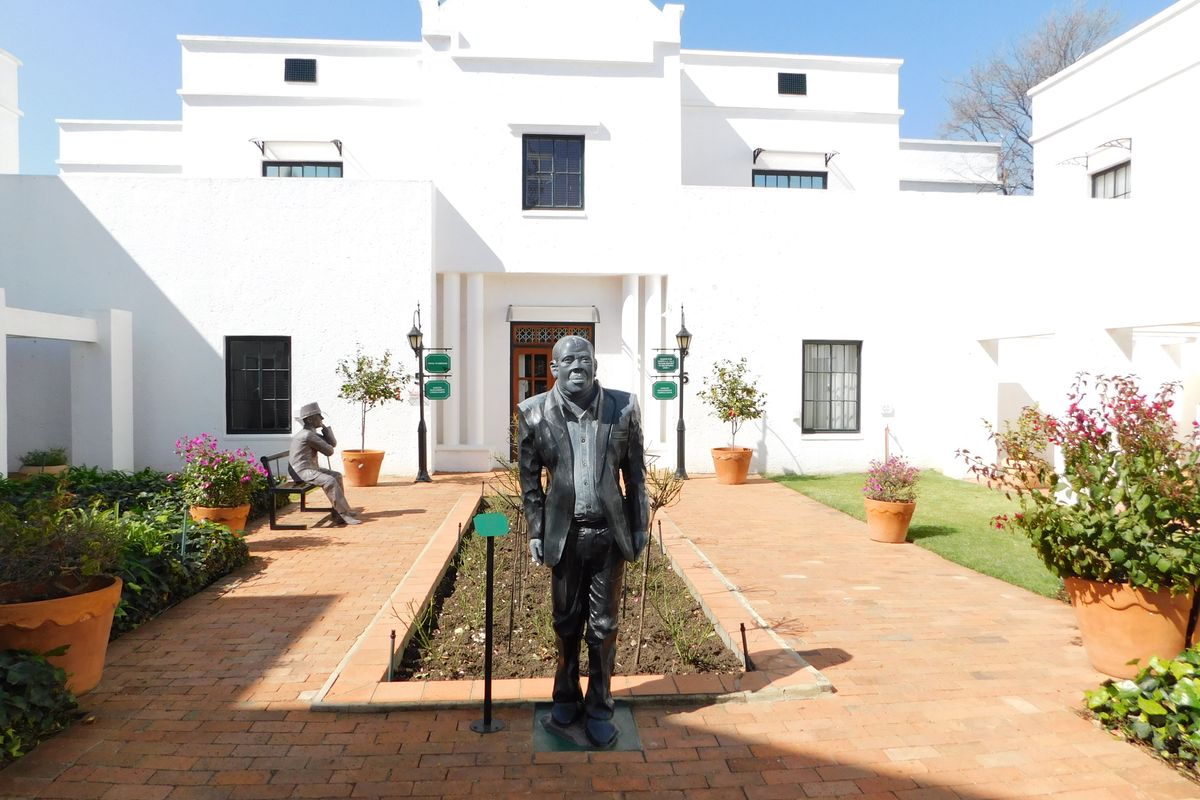 A well-maintained office courtyard featuring brick paving, raised garden beds, and a white building facade with classic architectural detailing.