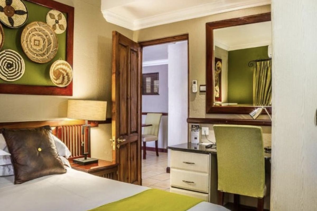 A well-maintained bedroom featuring a built-in vanity unit, wooden door, and tiled flooring, with a view into the adjacent room.