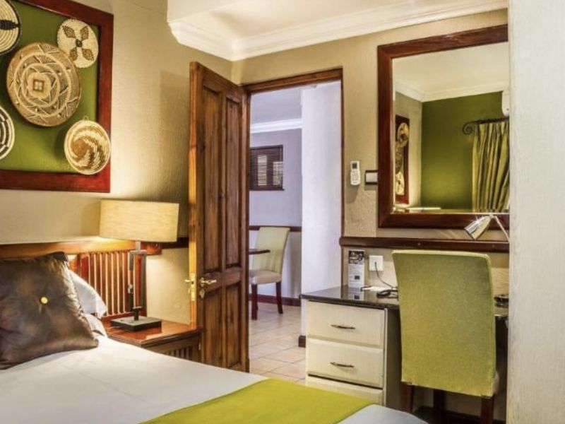 A well-maintained bedroom featuring a built-in vanity unit, wooden door, and tiled flooring, with a view into the adjacent room.