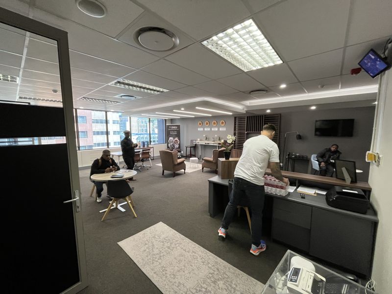 A professional office space featuring a suspended ceiling, recessed lighting, air conditioning, and a built-in reception desk with glass partition entry.