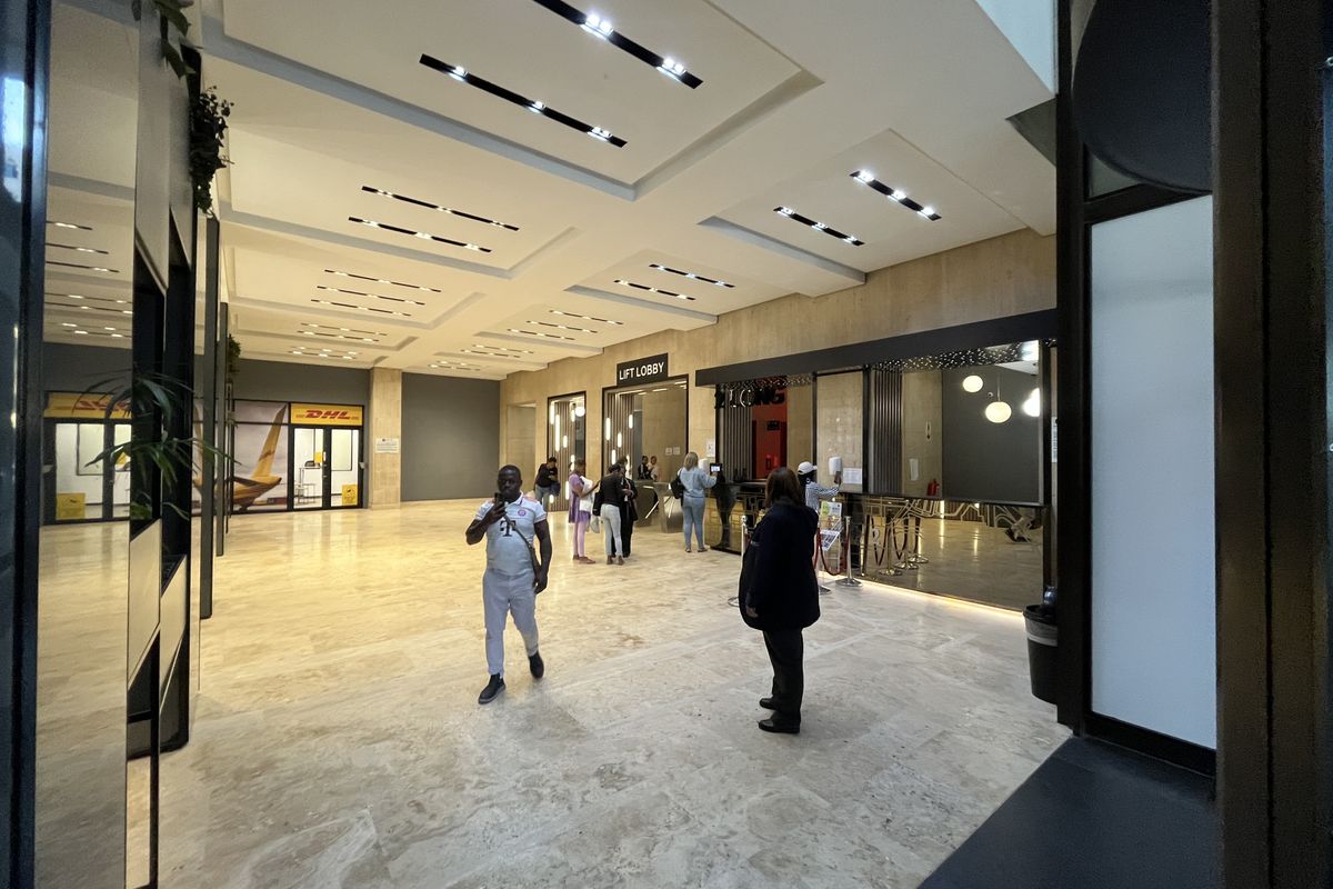 Spacious modern office building lobby featuring polished stone flooring, recessed ceiling lighting, and a dedicated lift lobby area.
