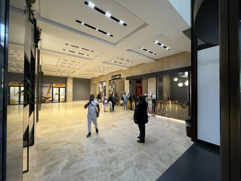 Spacious modern office building lobby featuring polished stone flooring, recessed ceiling lighting, and a dedicated lift lobby area.