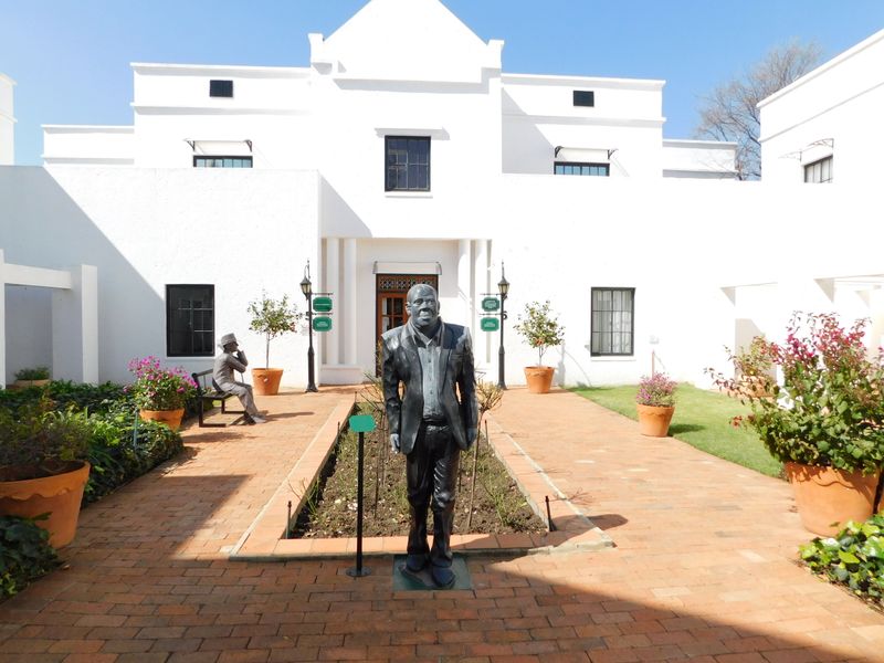 A well-maintained office courtyard featuring brick paving, raised garden beds, and a white building facade with classic architectural detailing.