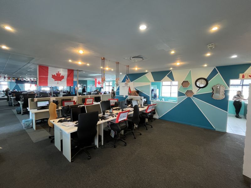Open-plan office space featuring carpeted flooring, recessed lighting, and a decorative geometric wall mural with integrated workstation partitions.