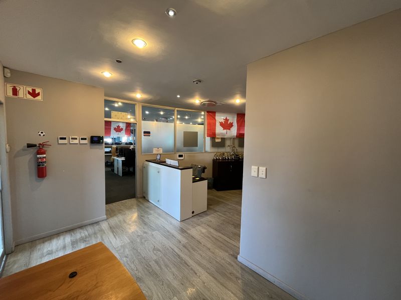 A professional office reception area featuring a built-in reception desk, glass partition walls, and modern recessed lighting with durable laminate flooring.