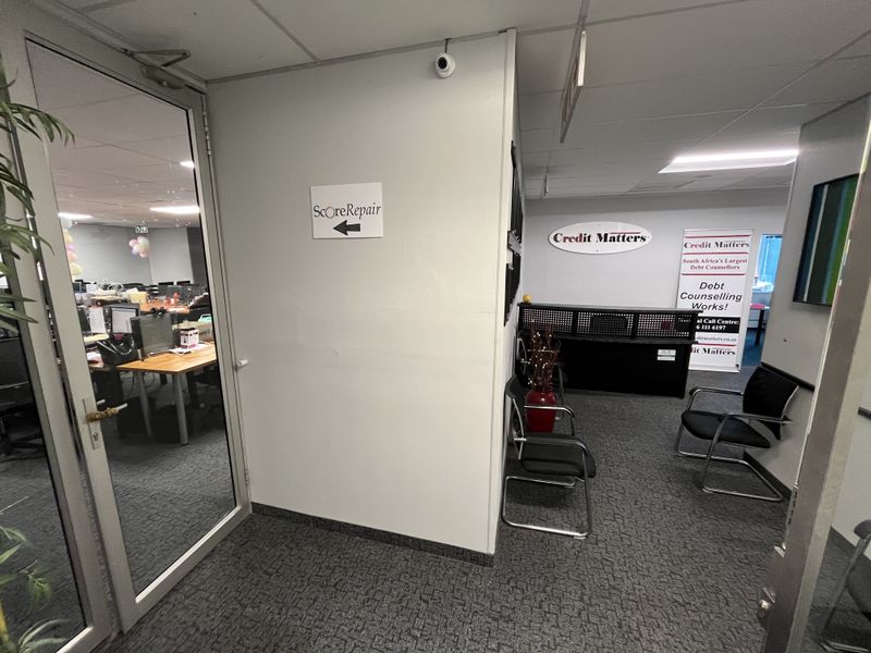Office reception area featuring a glass partition door, suspended ceiling, and a dedicated reception desk space.