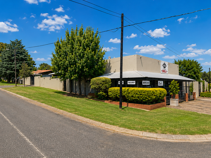 A well-maintained corner restaurant property featuring a paved parking area, covered veranda, and landscaped grounds with excellent street visibility.